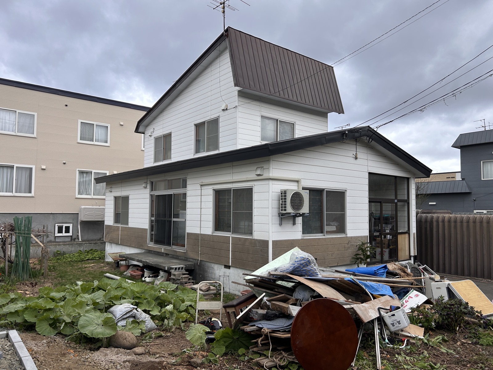 施工前の建物外観。カーポートは昨年弊社で施工済み。建物周囲に残置物が散在している状態