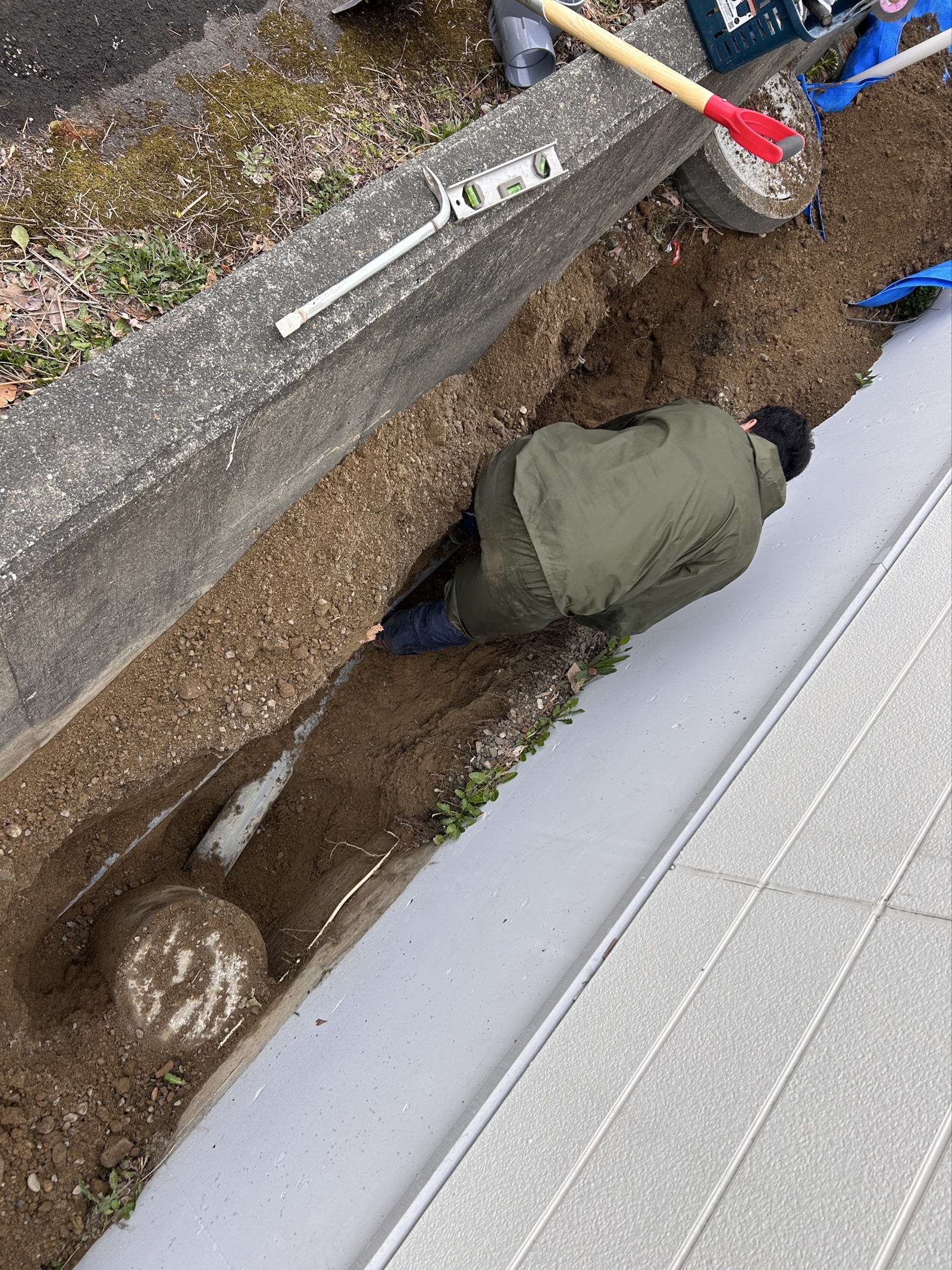 掘削作業中：スタッフが狭い溝の中に体を入れて手掘りで丁寧に掘り進める