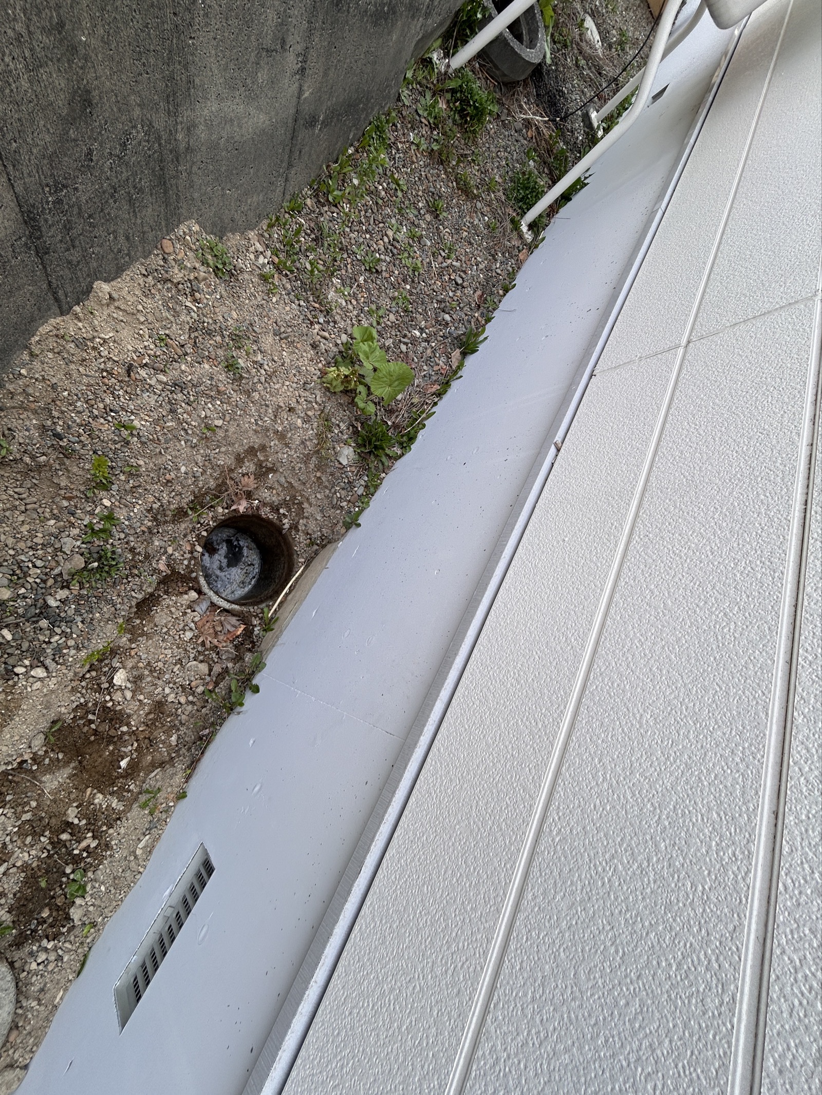 施工前：建物側面から見た排水マスの位置。水が引かず滞留しているのが確認できる