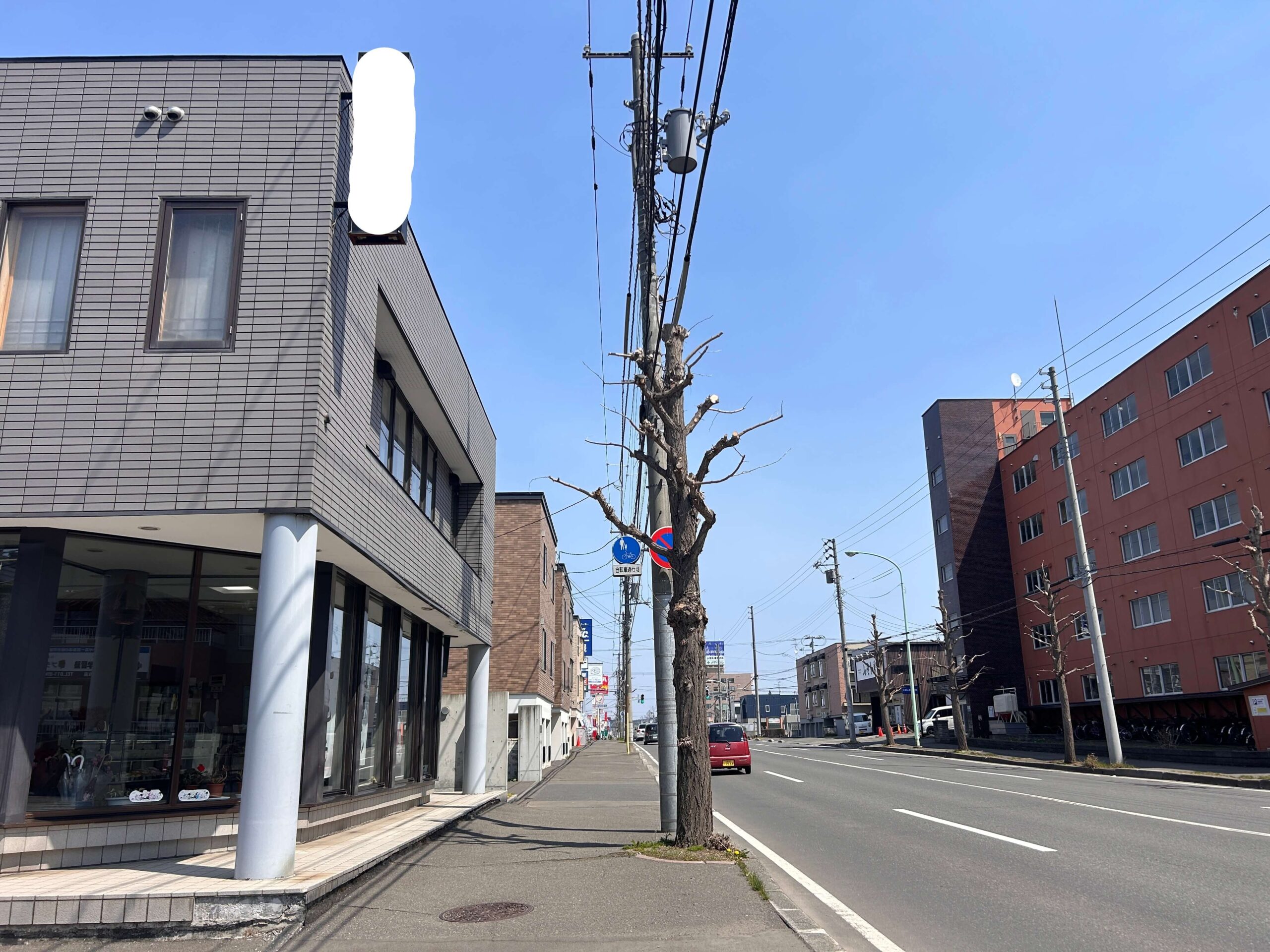 施工前：札幌市厚別区の幹線道路沿いに設置された老朽化した袖看板。遠目では目立つ位置にあるが、底面パネルが脱落している状態。