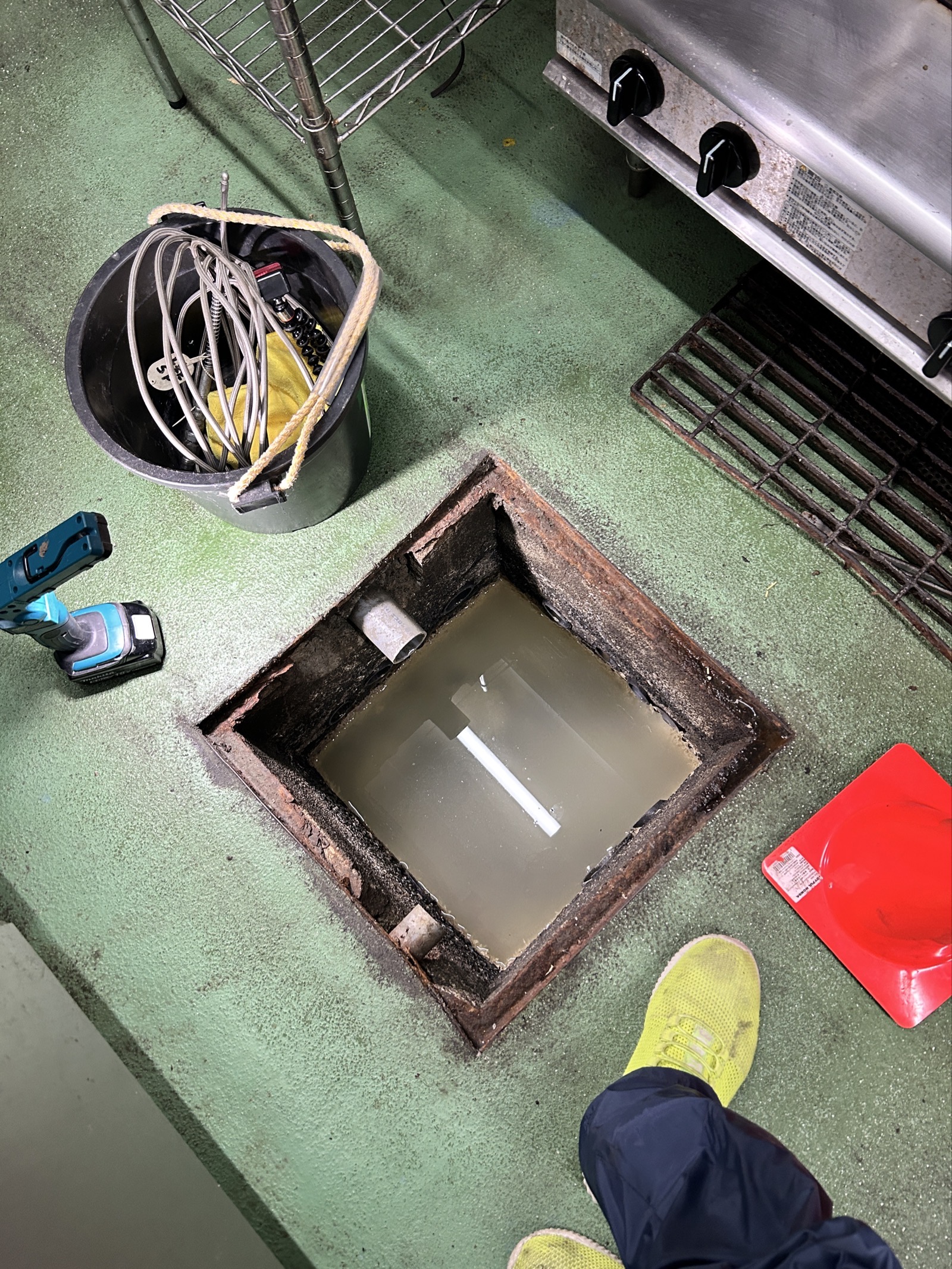 グリストラップ内に汚水が溢れかけた状態。油脂層と汚泥が底に堆積し、排水管が閉塞していた