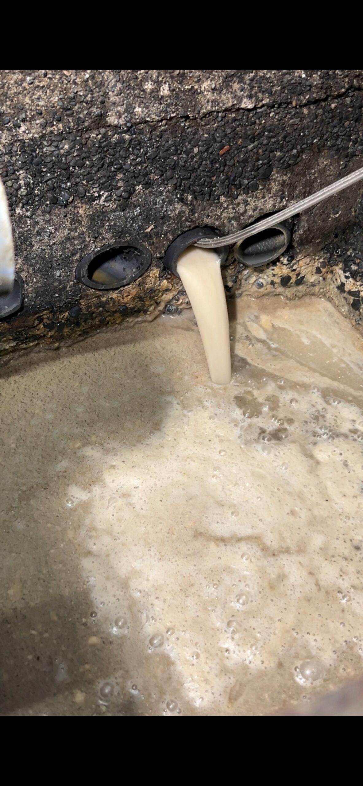 洗浄が進むにつれ、管から流れ出る水の色が薄くなってきた段階。油膜剥離が進んでいる証拠