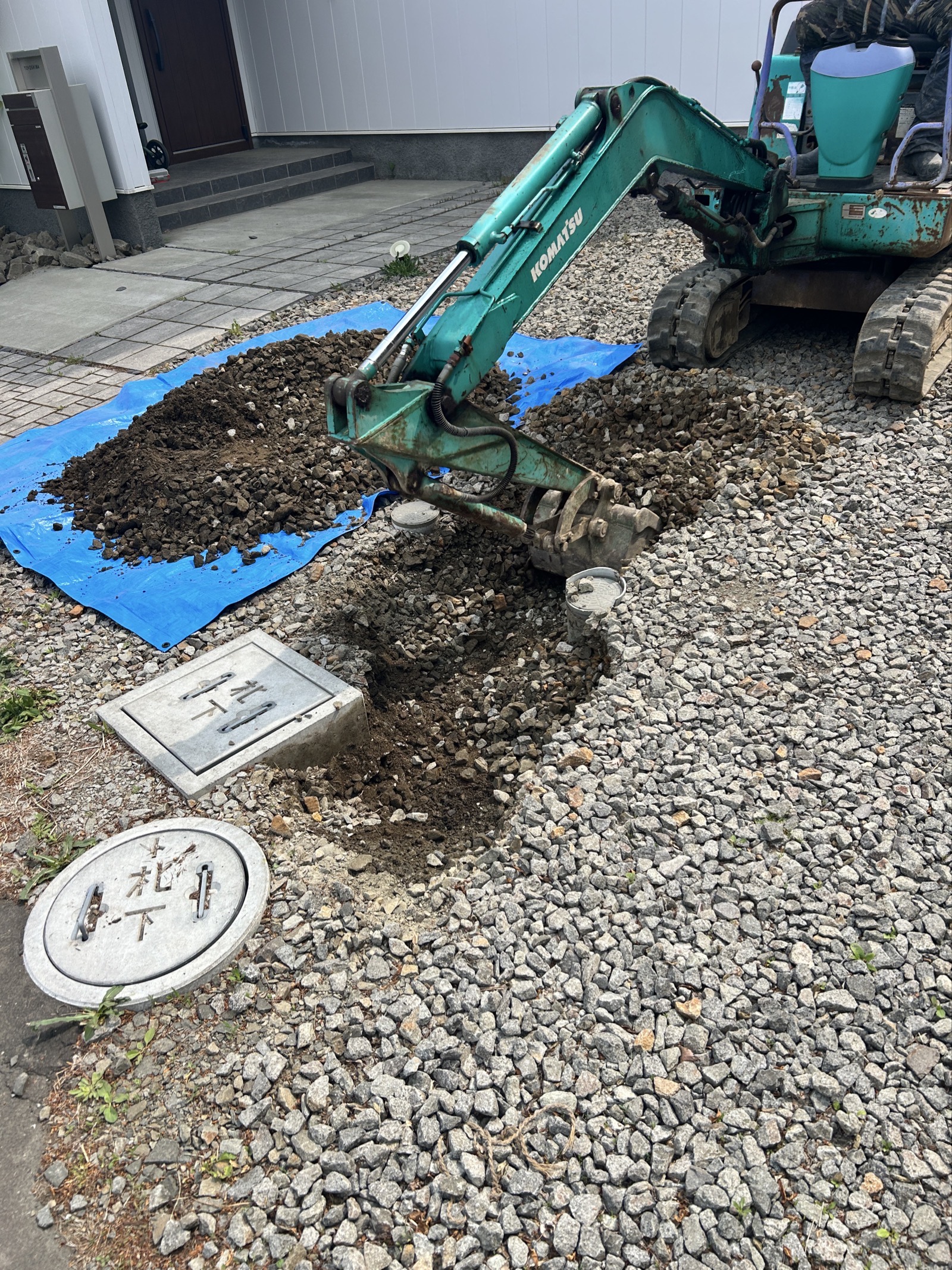 掘削開始:ミニバックホウで排水マス周辺を掘削。ブルーシートに掘削土を仮置きしながら進める