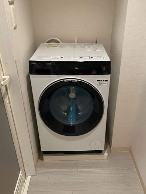 洗濯機底部と排水口の状況。排水ホースや配線が入り組み、横移動が困難な設置環境