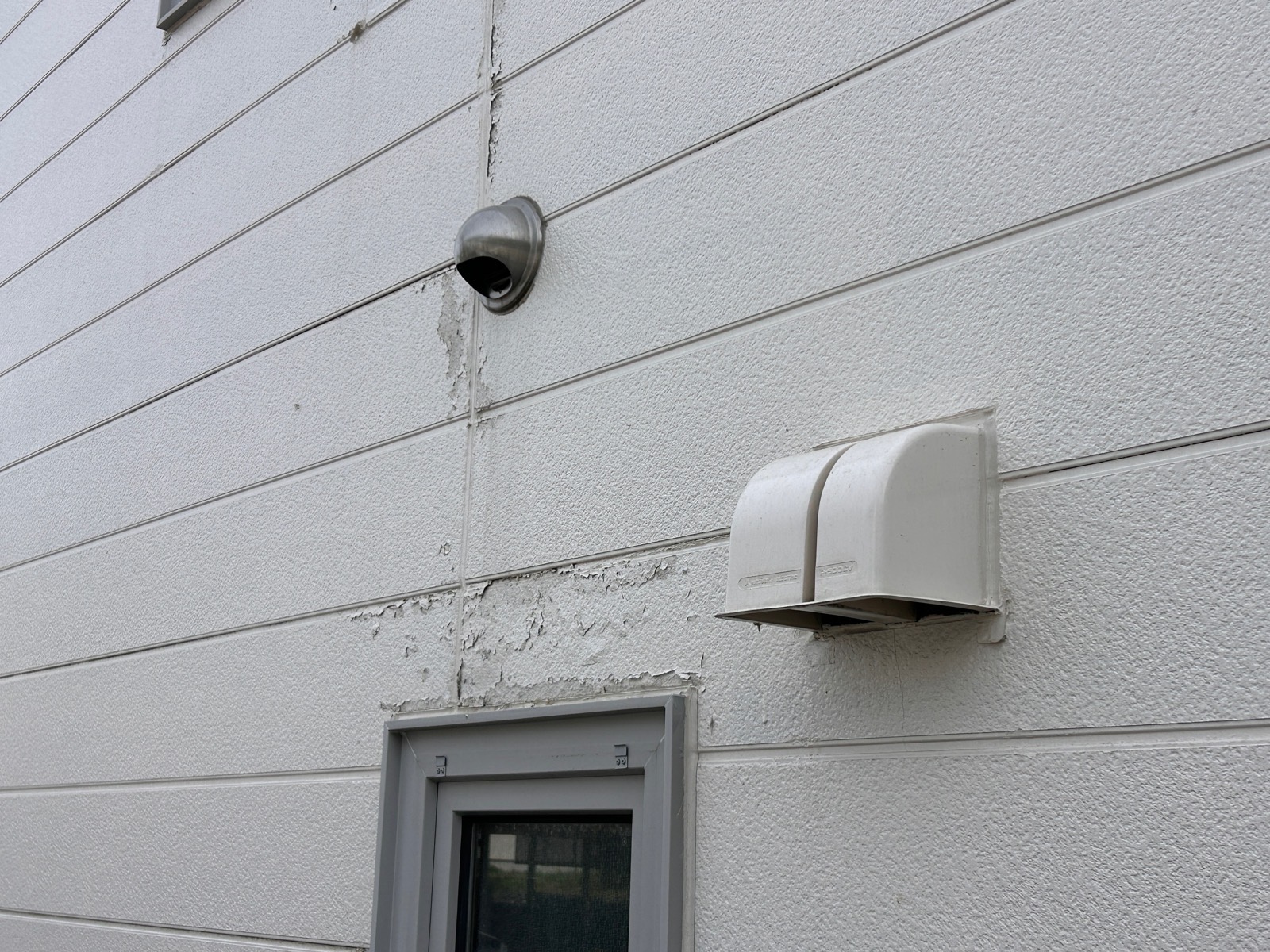 凍害発生箇所を正面から確認。塗膜が広範囲にわたって浮き上がり、外壁材の欠損も生じている。打診検査で浮きの範囲を特定した。