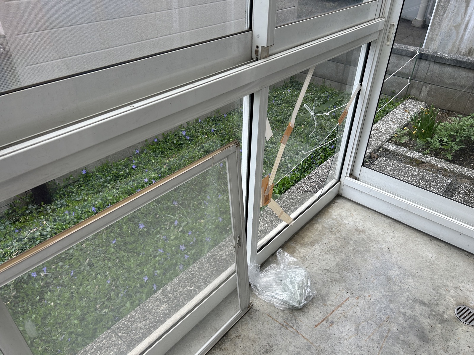 施工前：割れたガラスに養生テープが貼られた状態。複数箇所にひびが入っていた