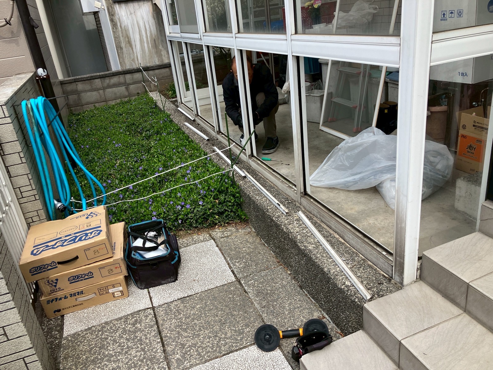 作業中：ガラス撤去後、サッシ枠だけが残った状態と資材の搬入