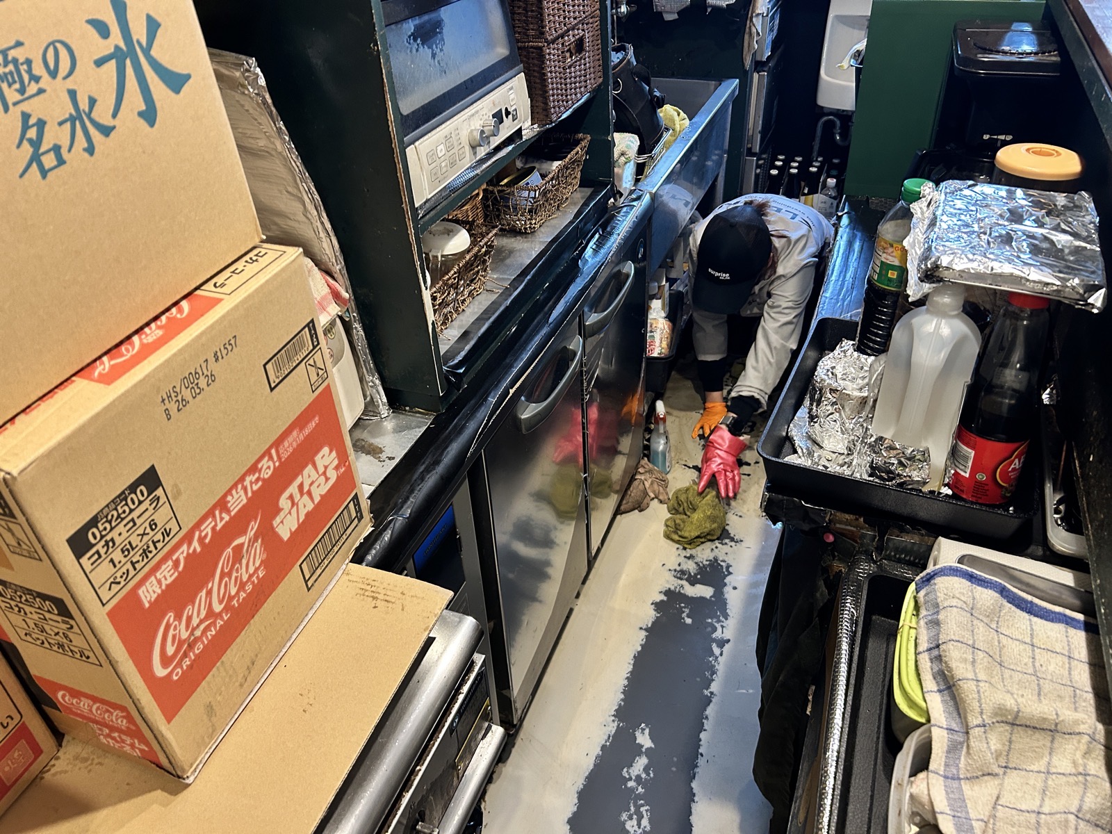 厨房床の清掃作業中。固着した油汚れにアルカリ洗剤を浸透させながら除去。