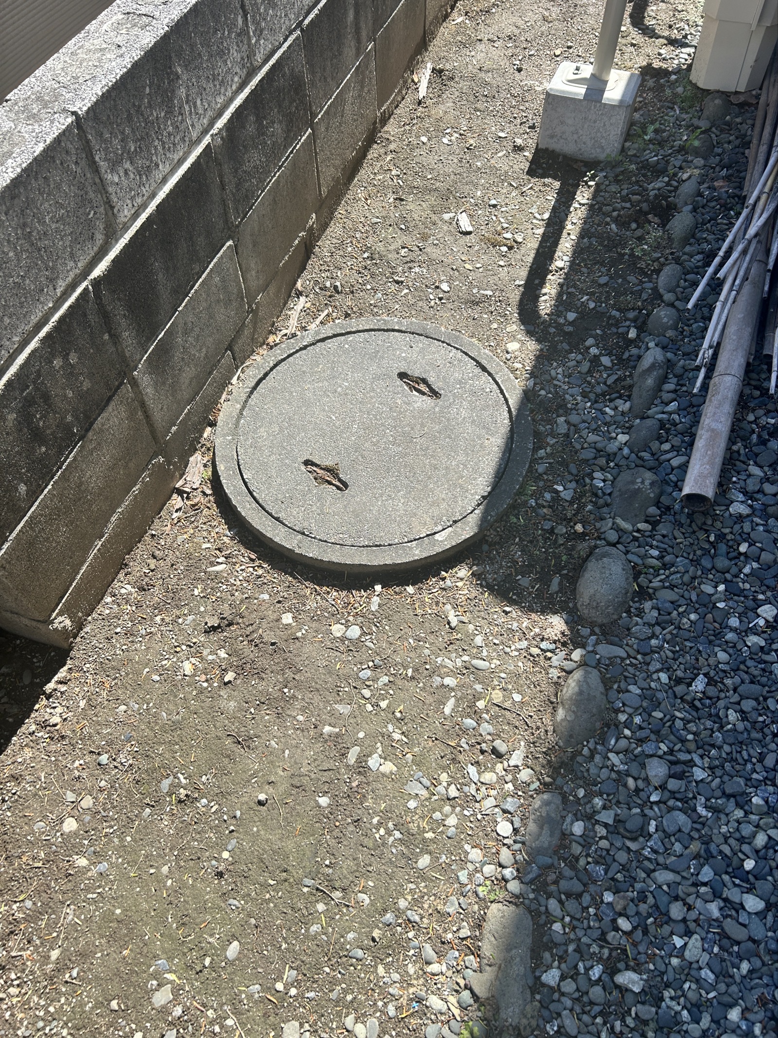 排水マス交換工事前の状態。建物際に設置されたコンクリート製排水マスの蓋。外径約660mmの大型マスで、繰り返すトイレ詰まりの原因となっていた