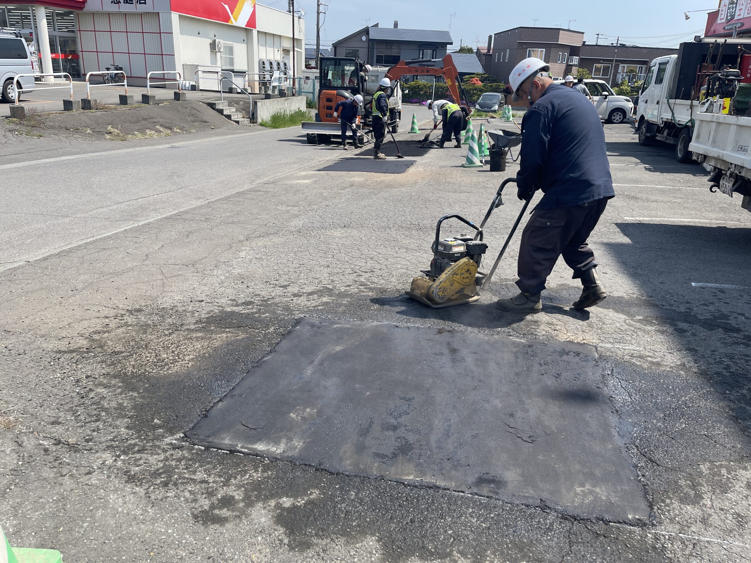 アスファルト補修の最終工程、プレートコンパクターで路面を均一に締め固める作業