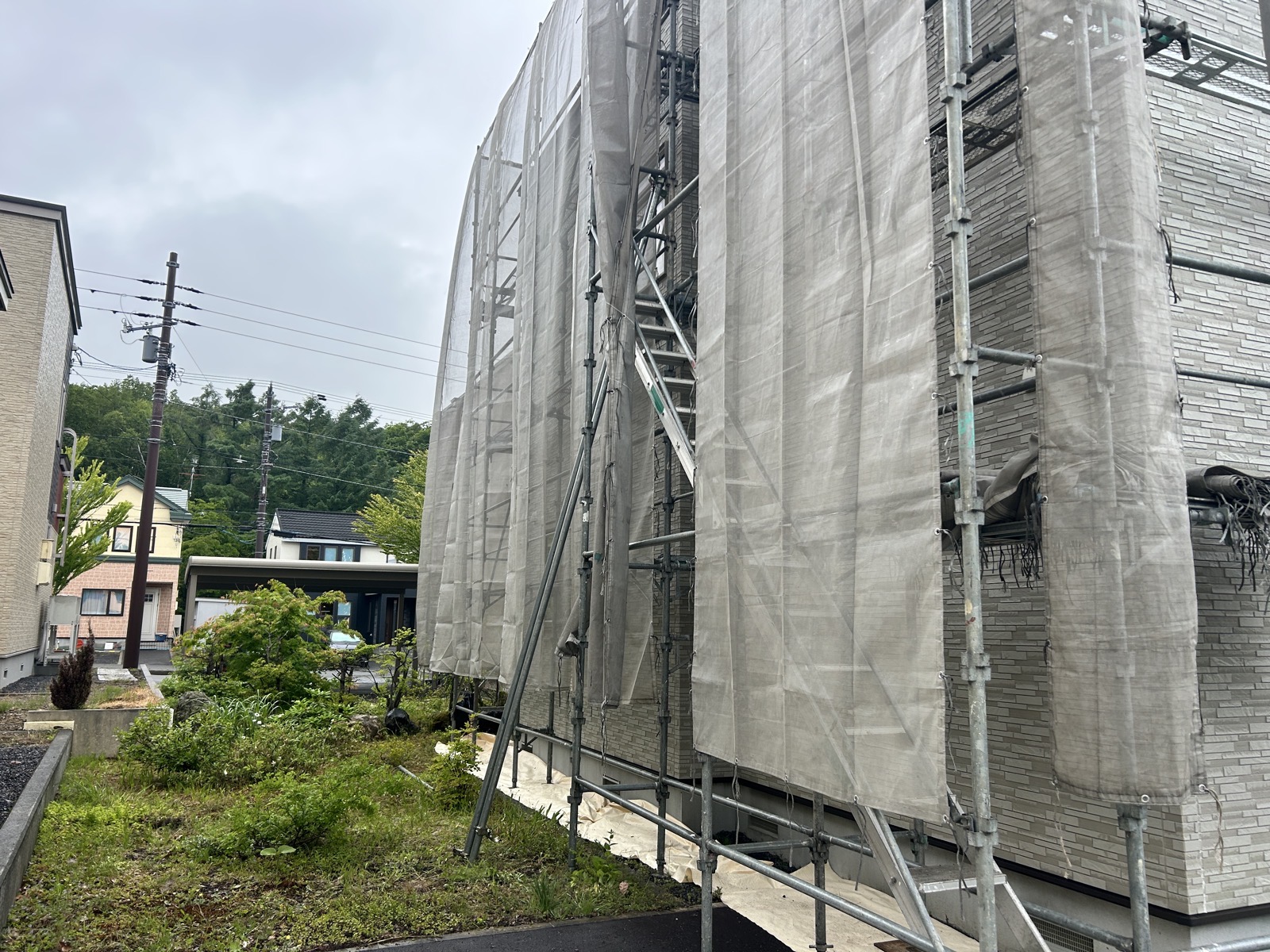 外壁凍害の補修工事で足場・飛散防止メッシュを設置した戸建て全景（札幌市清田区）