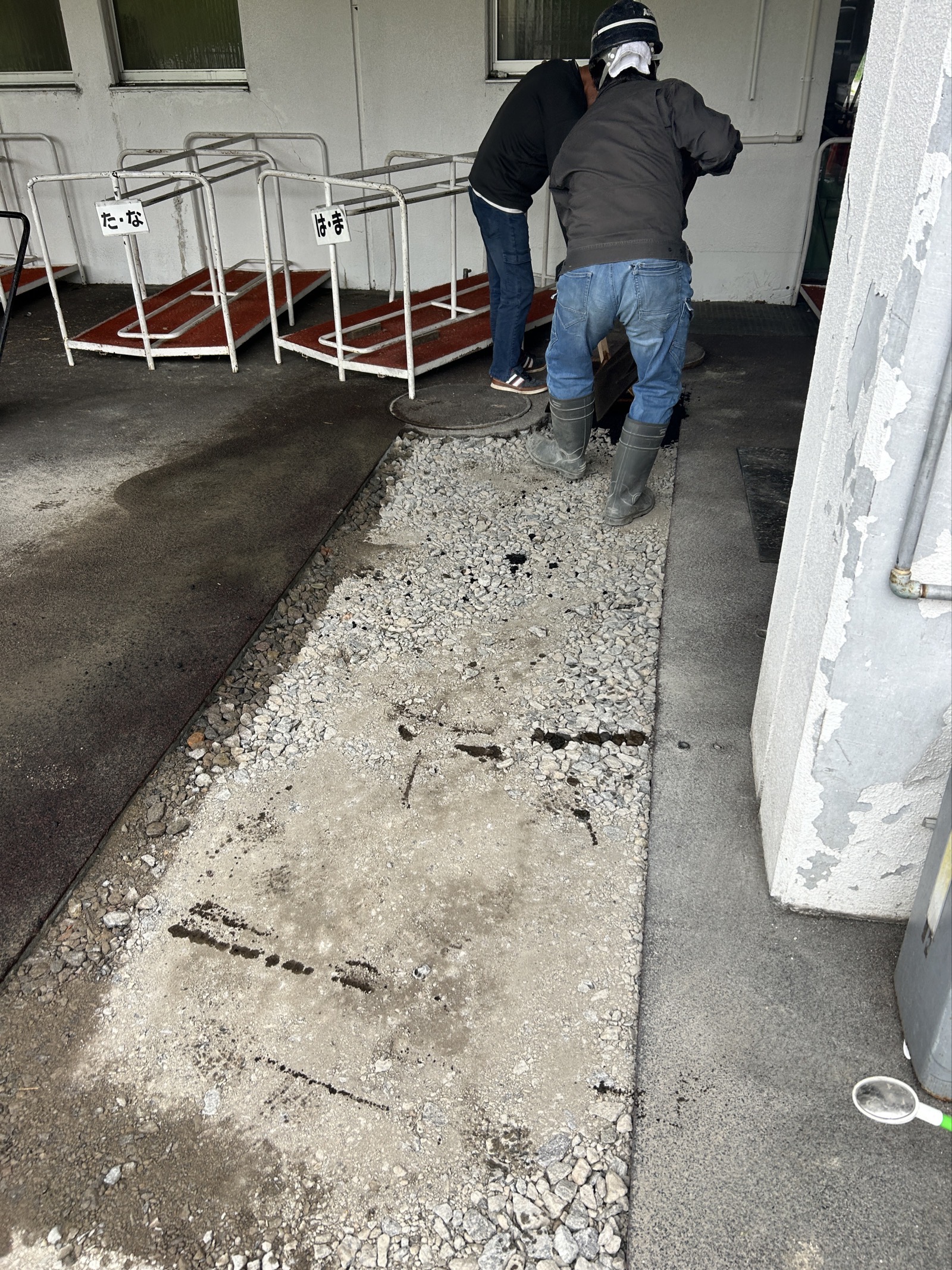 アスファルト舗装 本復旧の施工前の状態。排水管工事後の仮復旧部分と砕石が露出した路面
