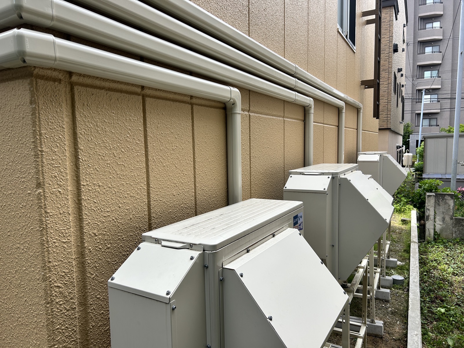 完工後:建物裏手に整然と並んだ室外機。落雪経路からも隣地境界からも距離が確保されている