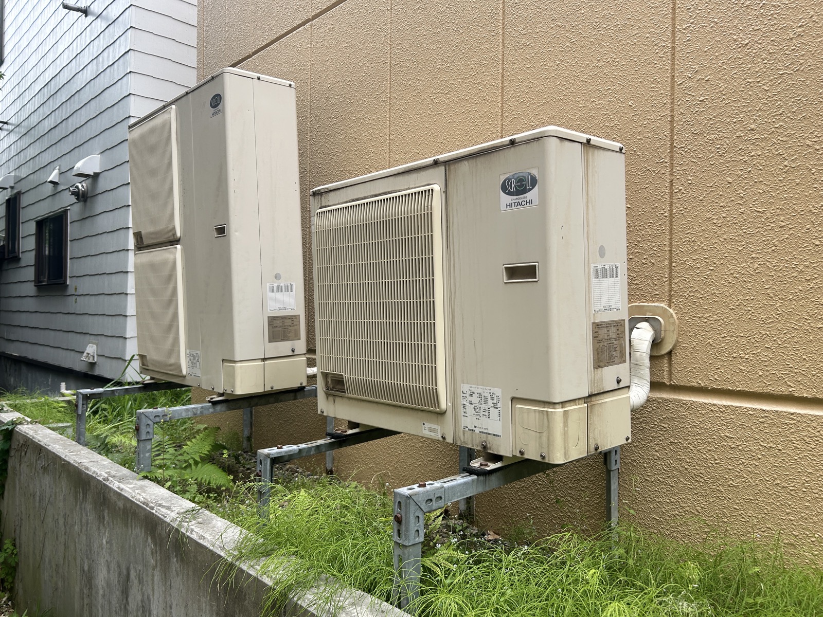 撤去前の状態。壁面架台に設置された業務用エアコン室外機2台（HITACHI製）。長年使われていなかった機器が建物裏手に並んでいた
