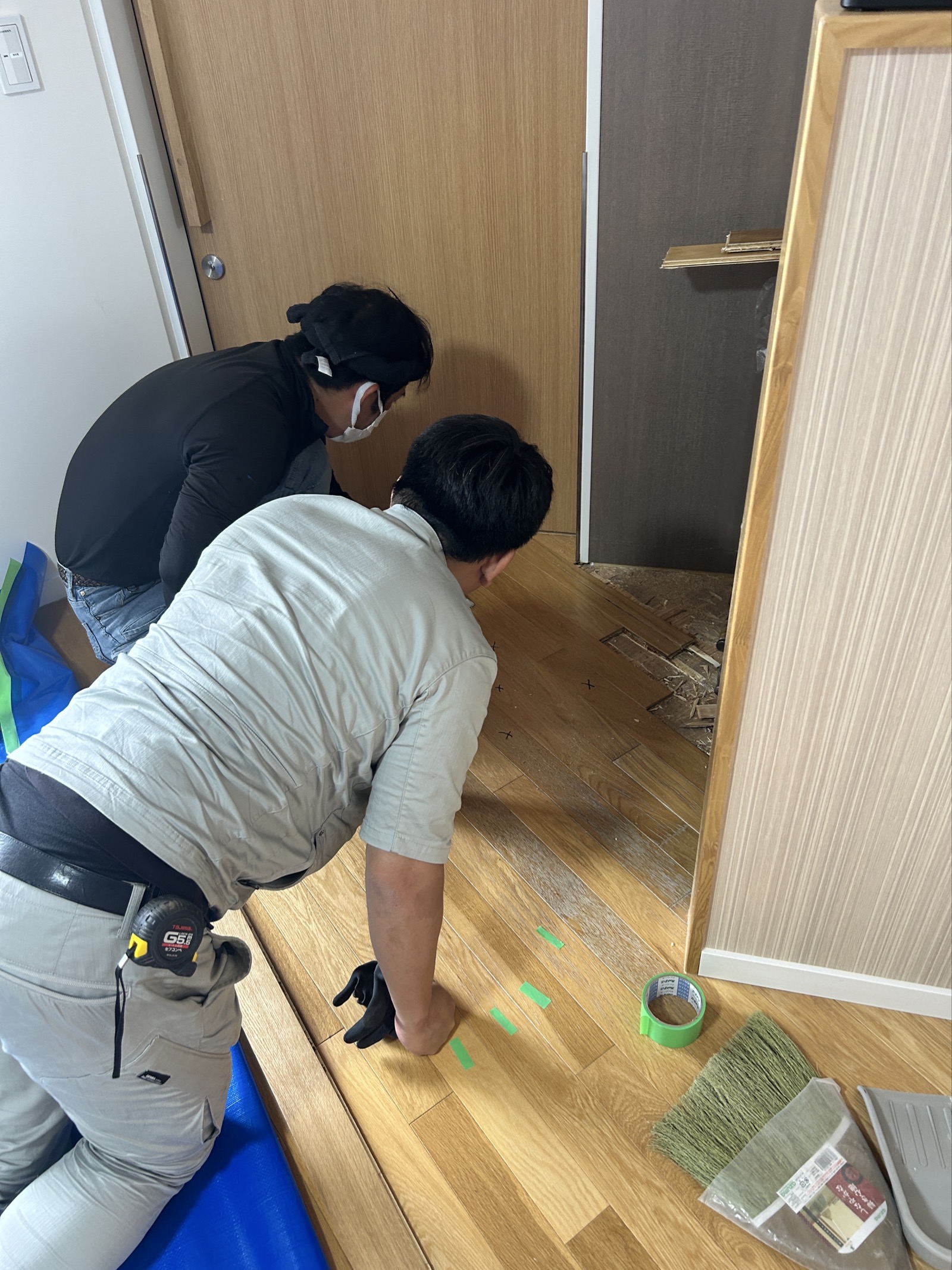 2名で下地の状態と新材の貼り出し基準位置を確認している様子