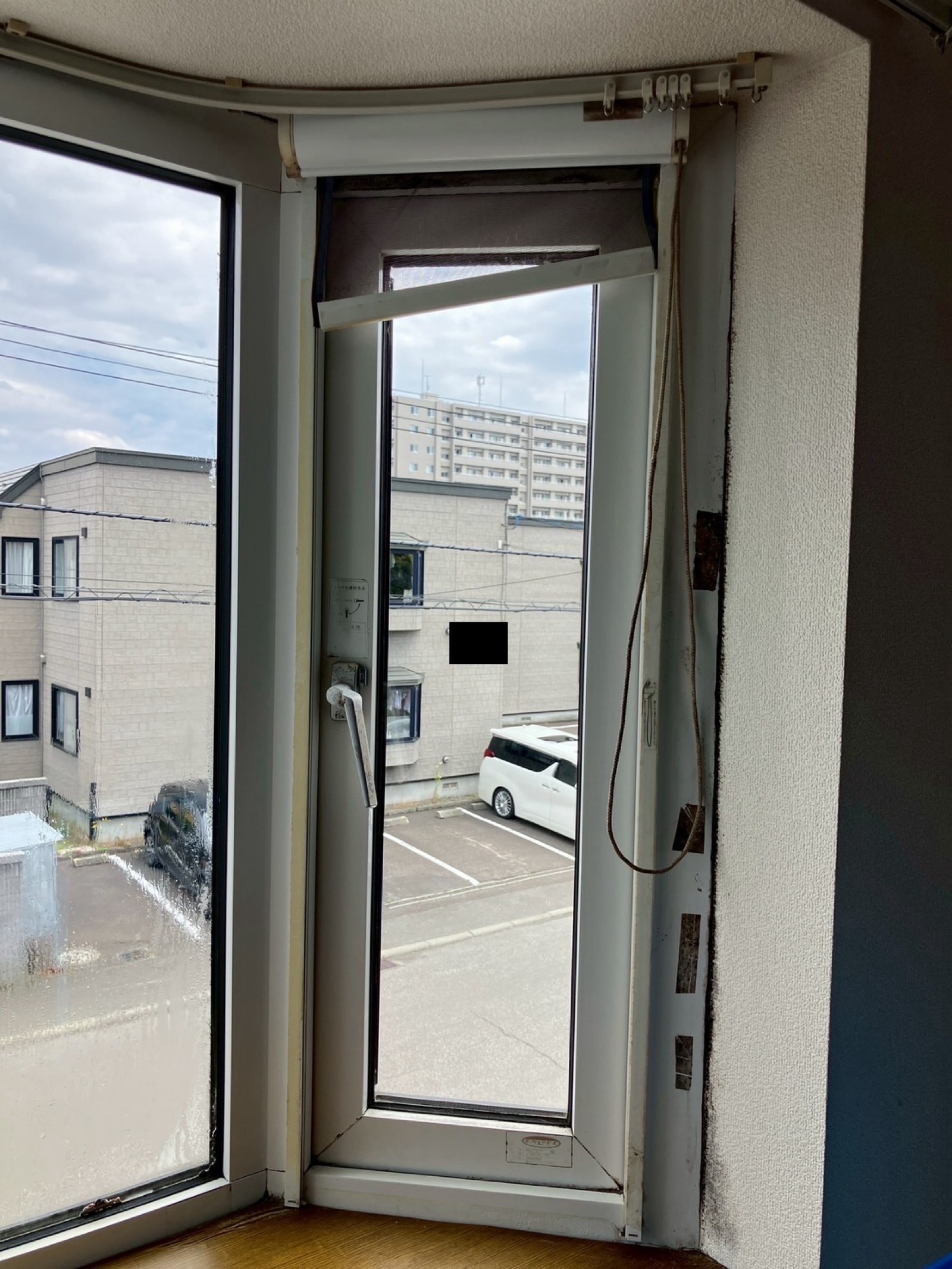 網戸交換 賃貸アパート2階・縦すべり出し窓の既設網戸が劣化・変形している状態(交換前)