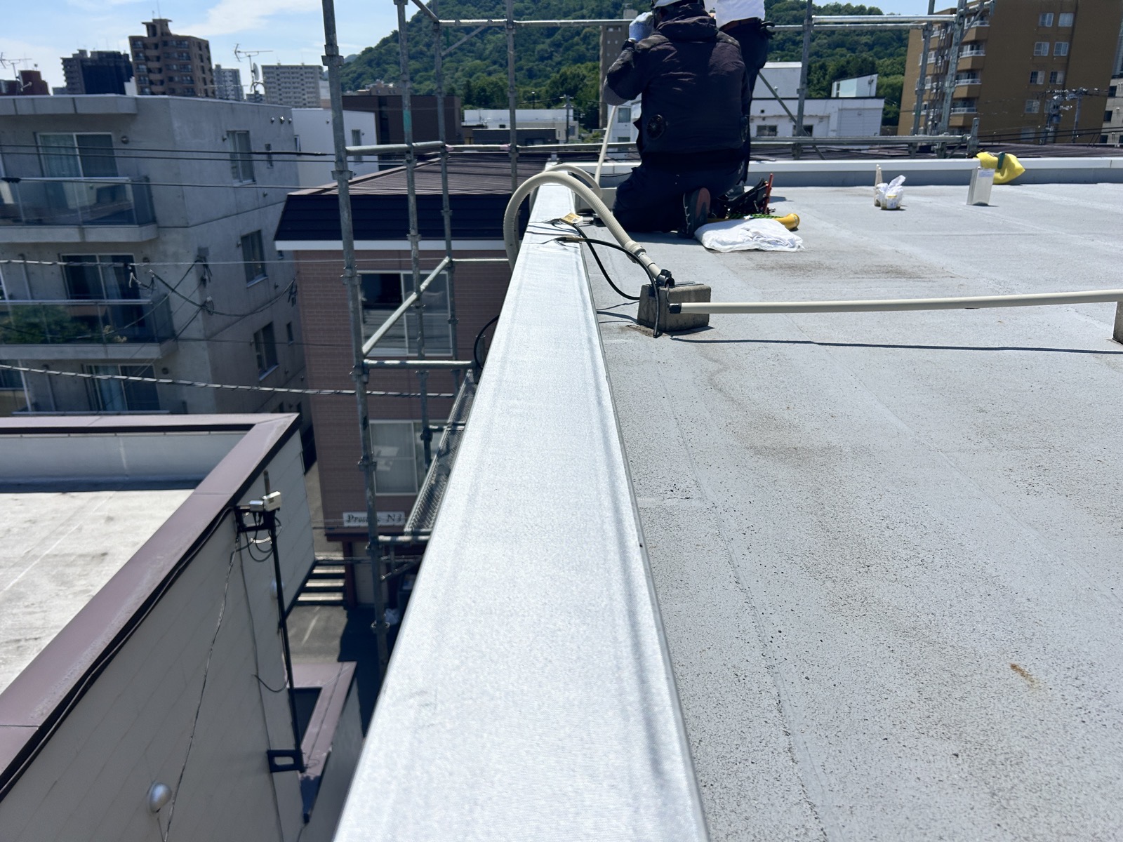 外壁面の室外機横でPF管の配線経路を確認する電工。既存設備との干渉を事前に確認した