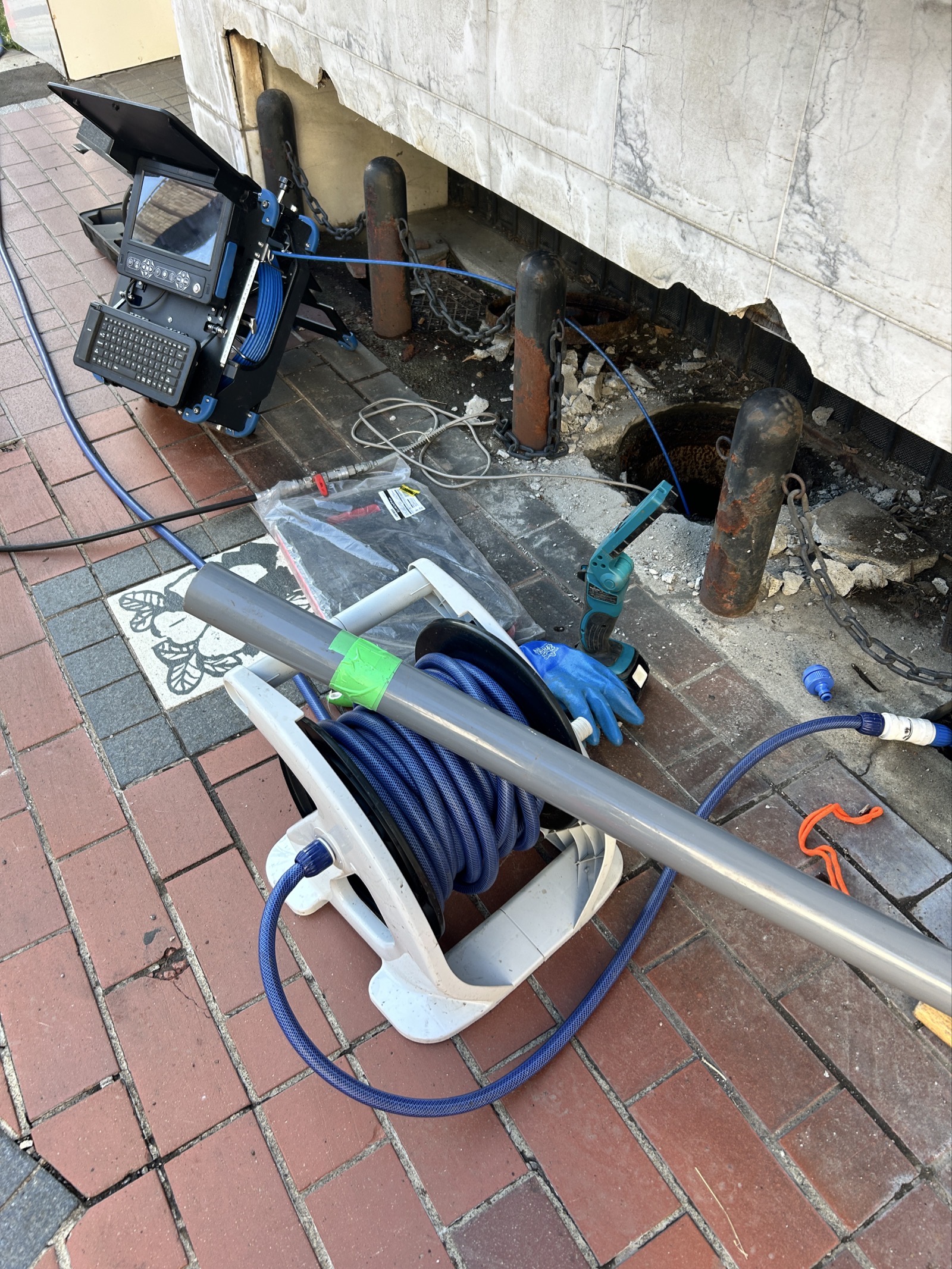 店舗前に設置した管内カメラ機材一式。モニター付き操作ユニット・ホースリール・挿入ロッドを配置し、リアルタイムで管内映像を確認しながら調査を進めた
