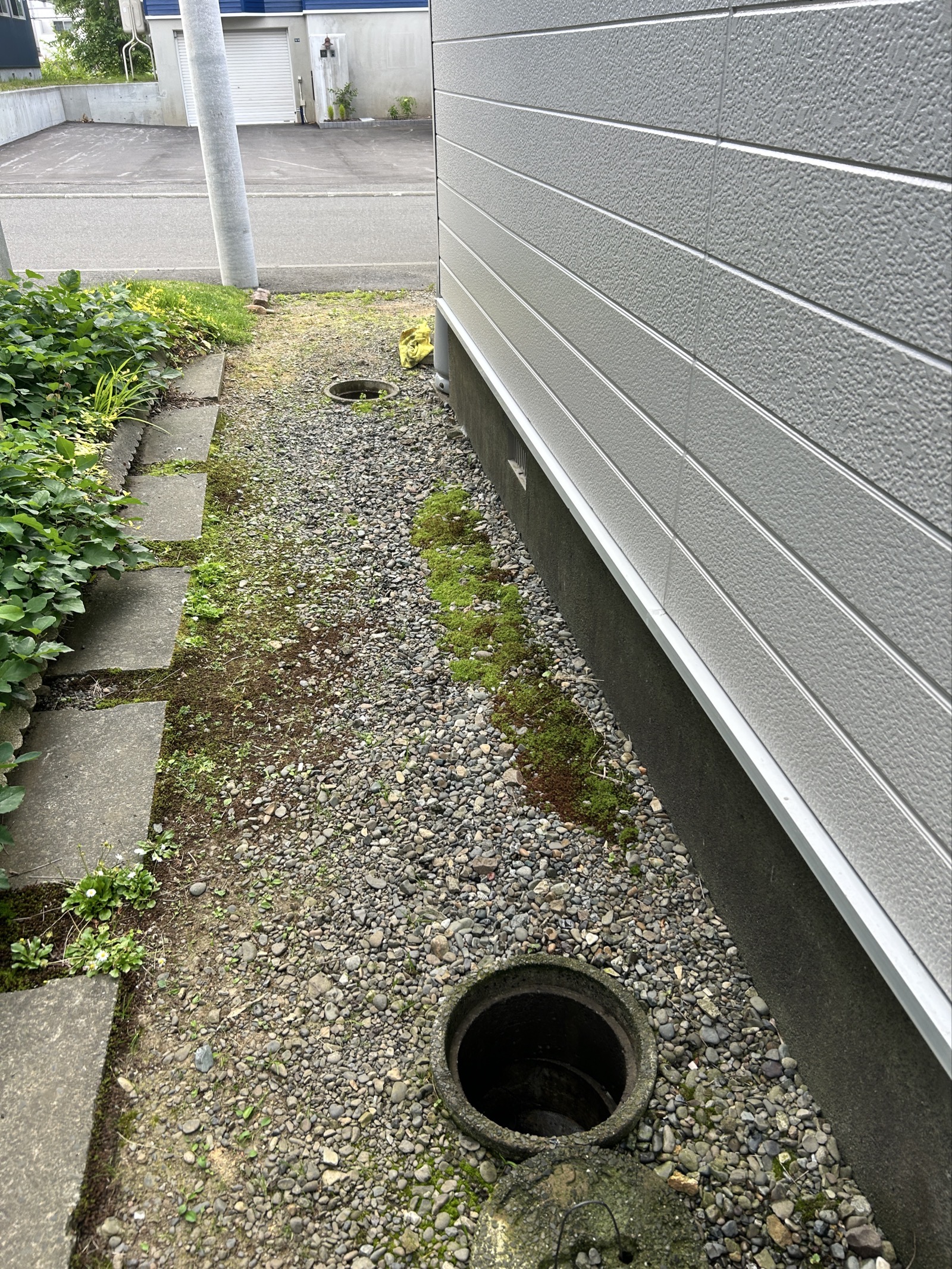 建物外壁沿いに並ぶ排水マスの点検口を開放して系統を確認している様子