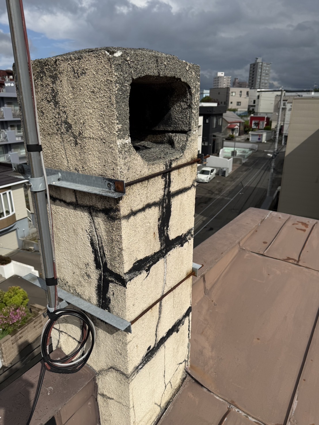 ひび割れが入り金属バンドで補強された既存の煙突