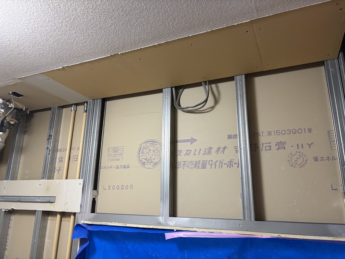 解体後の壁で吊り戸棚用の下地を確認するキッチン交換の作業風景（札幌市北区）