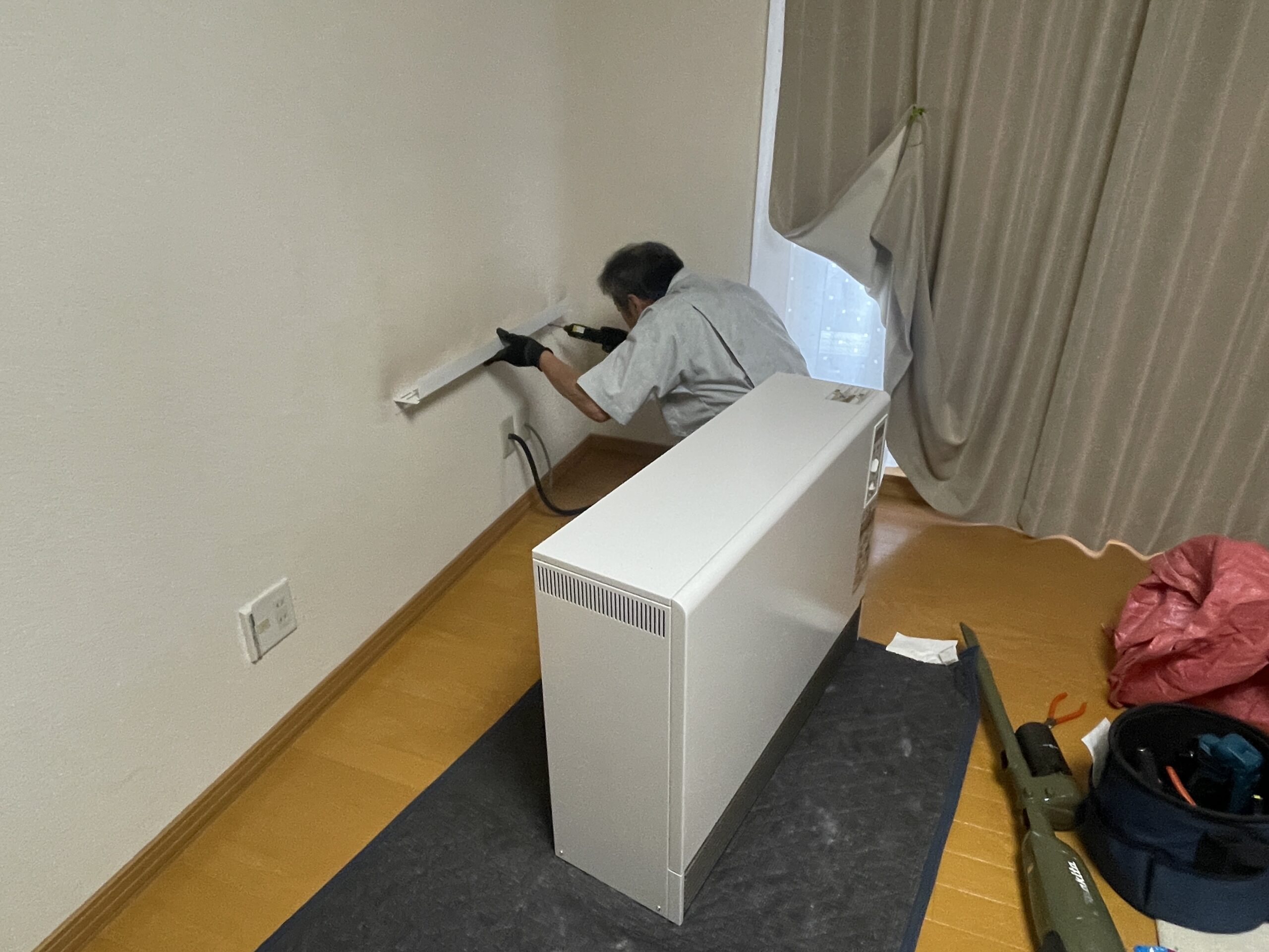 新しい蓄熱暖房器の設置後、電気屋さんによる配線接続作業の様子