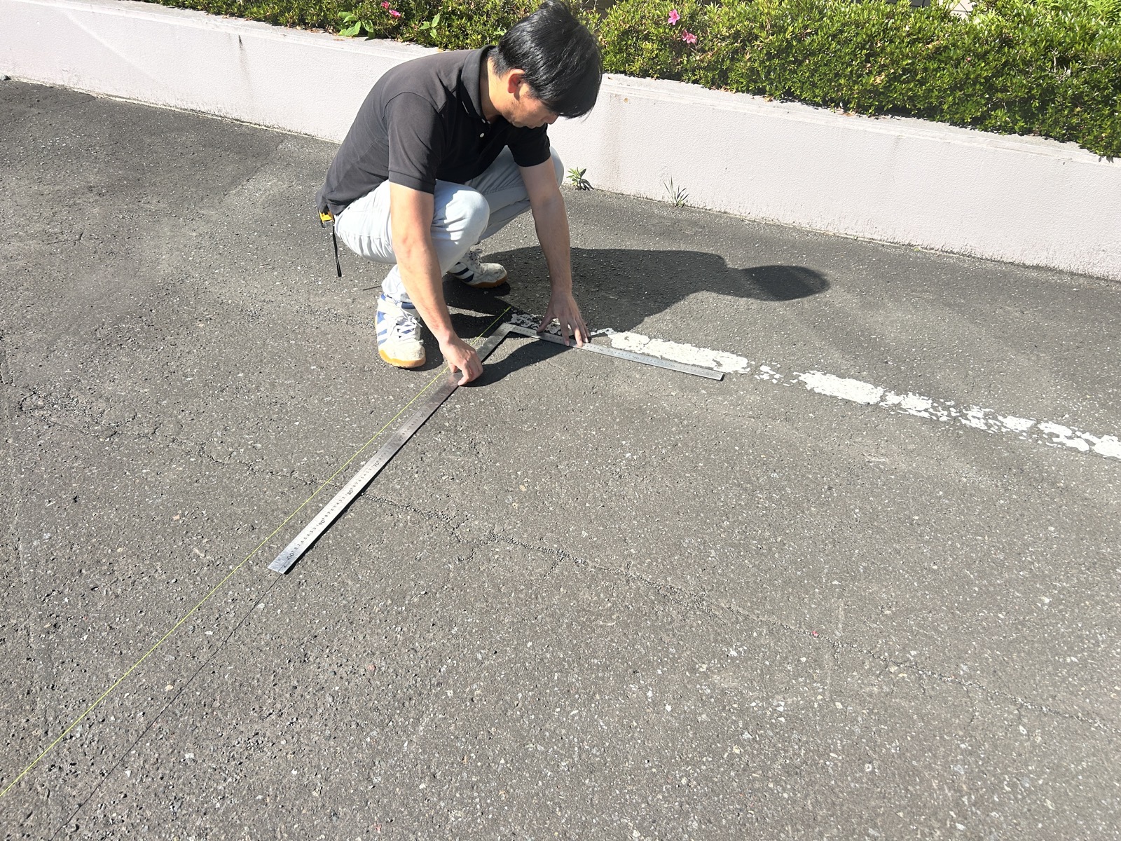 差し金とメジャーを使って車止めの設置位置を採寸する様子