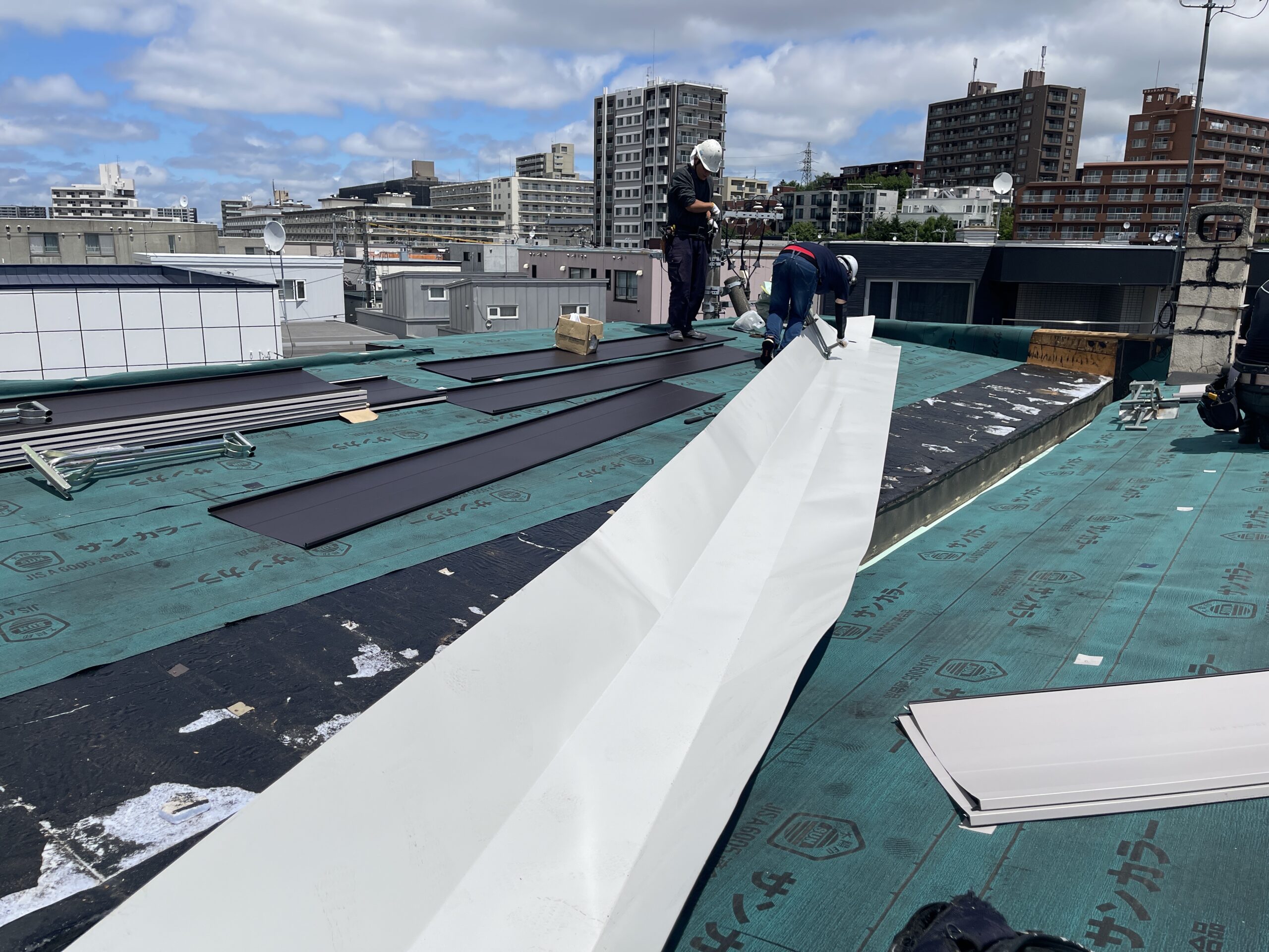 職人が新しい板金屋根材を設置している作業風景