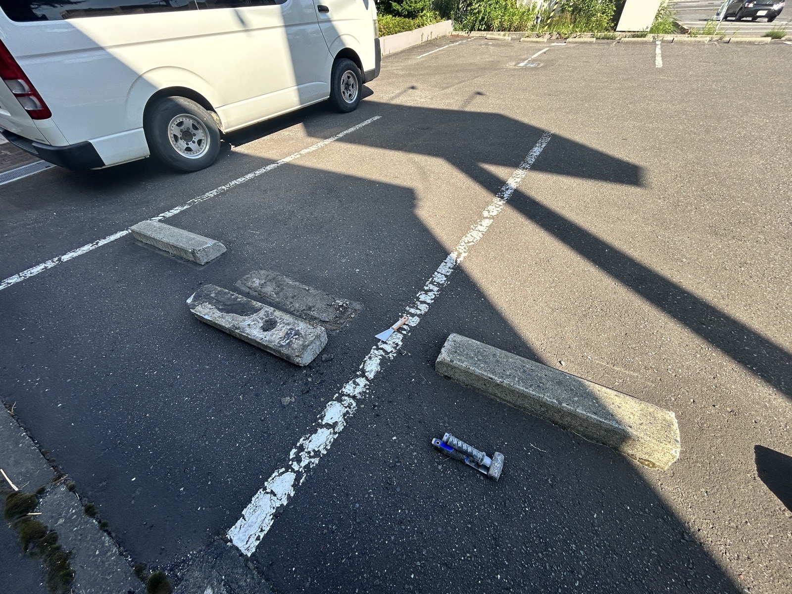 位置がずれて浮き上がった車止め(パーキングブロック)と剥がした既存ボンドの様子。車止め 修繕前の状態