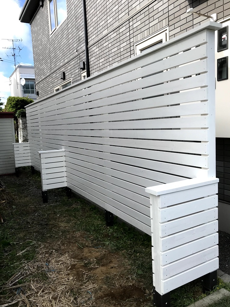 札幌市東区で造作した白い木製の目隠しフェンス。横板張りで隙間を設け、控えを兼ねた腰壁で補強している