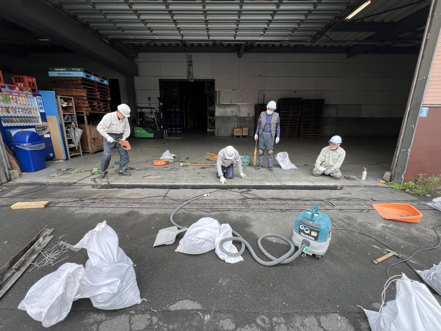 倉庫の出入口でアングル撤去とはつり作業を進める作業員と集じん機