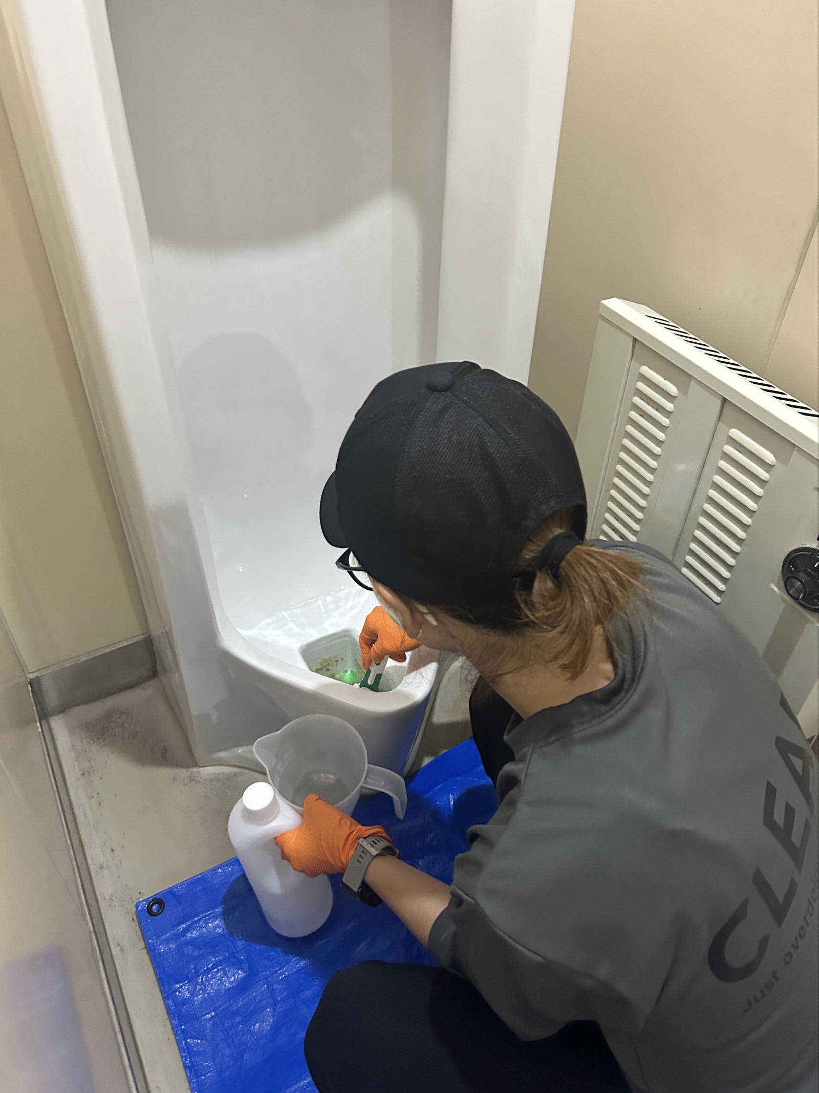 便器側のトラップ穴に尿石除去剤を投入する作業の様子