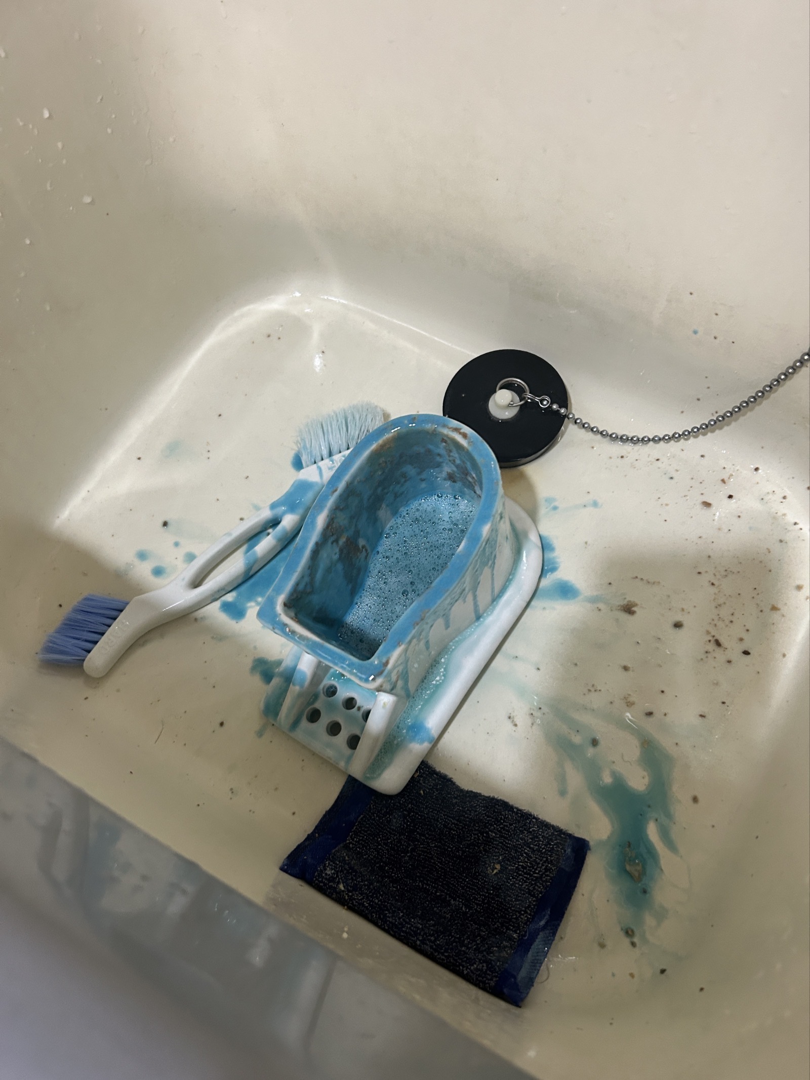 取り外したトラップ部品を洗い場で薬剤に浸けて洗浄している様子