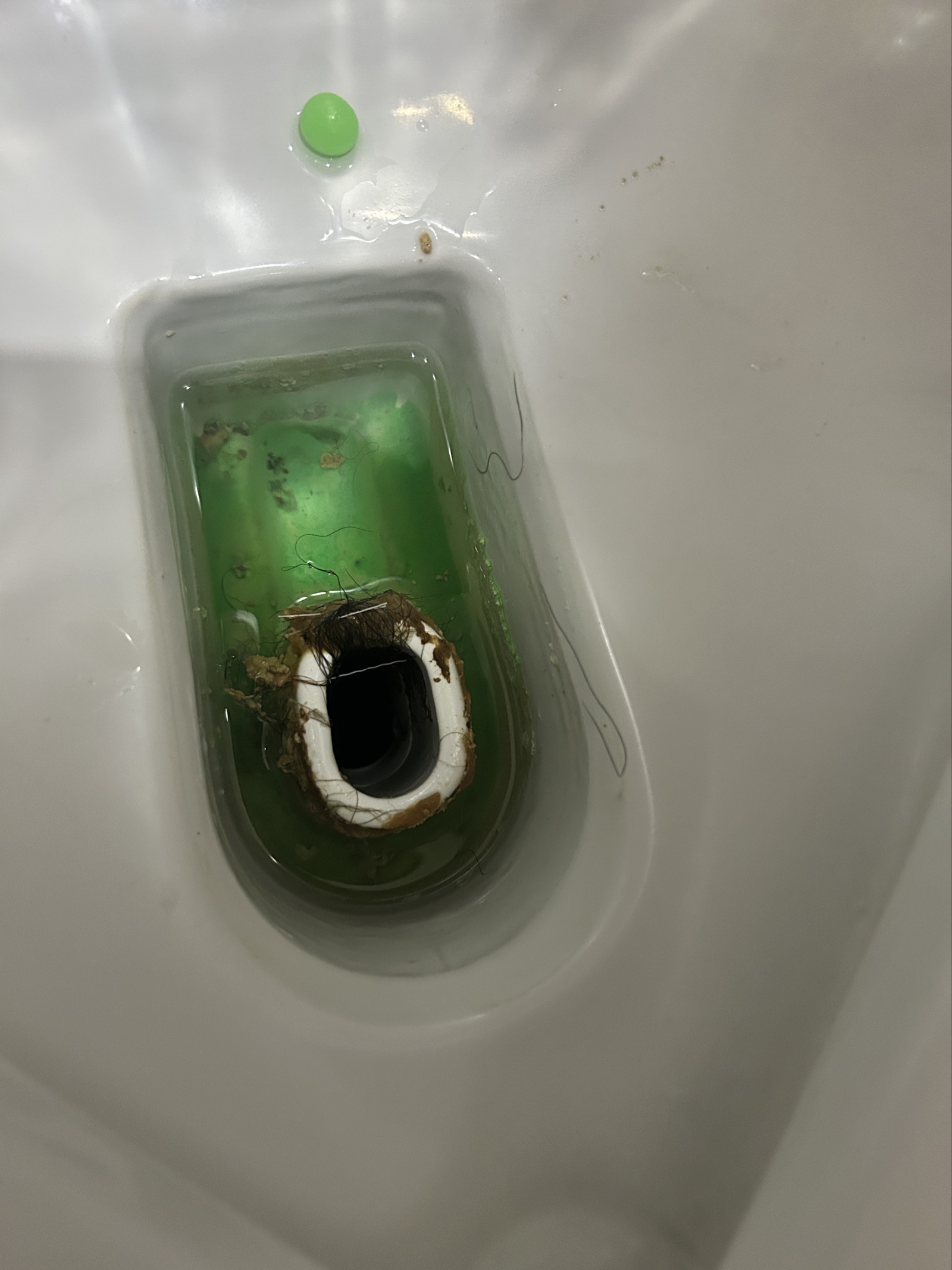 小便器 尿石が付着した清掃前のトラップ部。封水が変色し人毛や汚れが絡んでいる