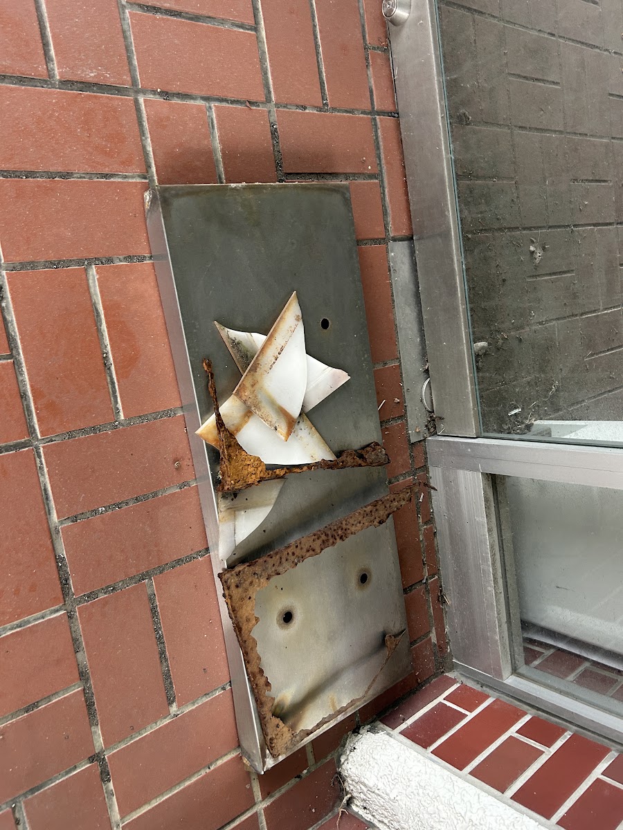 腐食して抜け落ちた看板底部の金属板と割れたアクリル板