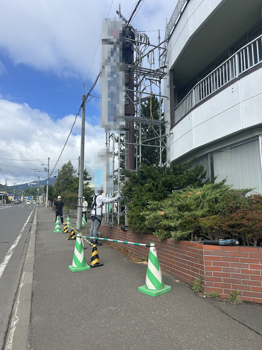 歩道側をカラーコーンと規制バーで区切り、通行人の安全を確保しながらの作業風景