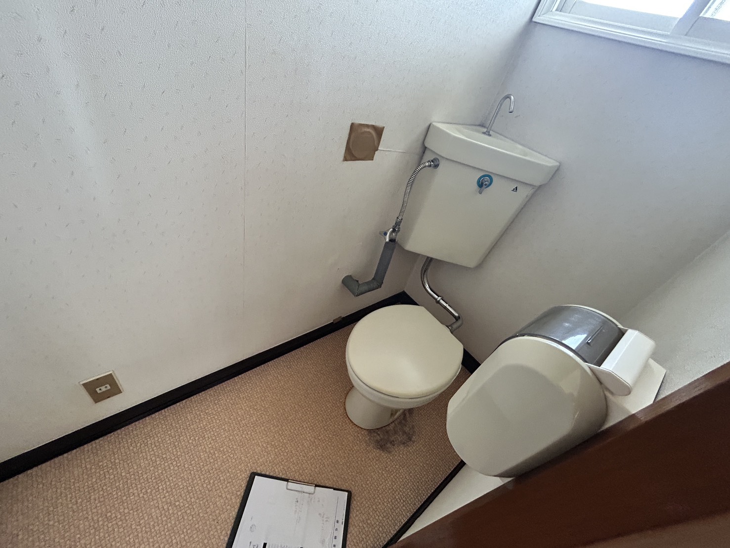施工前のトイレ全体、床のクッションフロアや壁紙に使用感が見られる