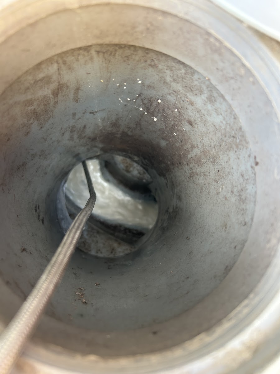 配管の入り口にワイヤー式の器具を挿入して洗浄している様子