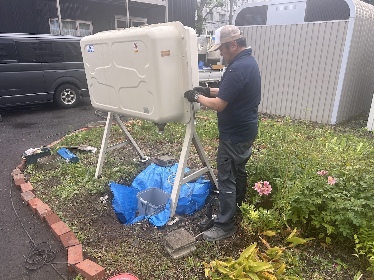 架台に載ったタンクを手で支えながら作業する作業員