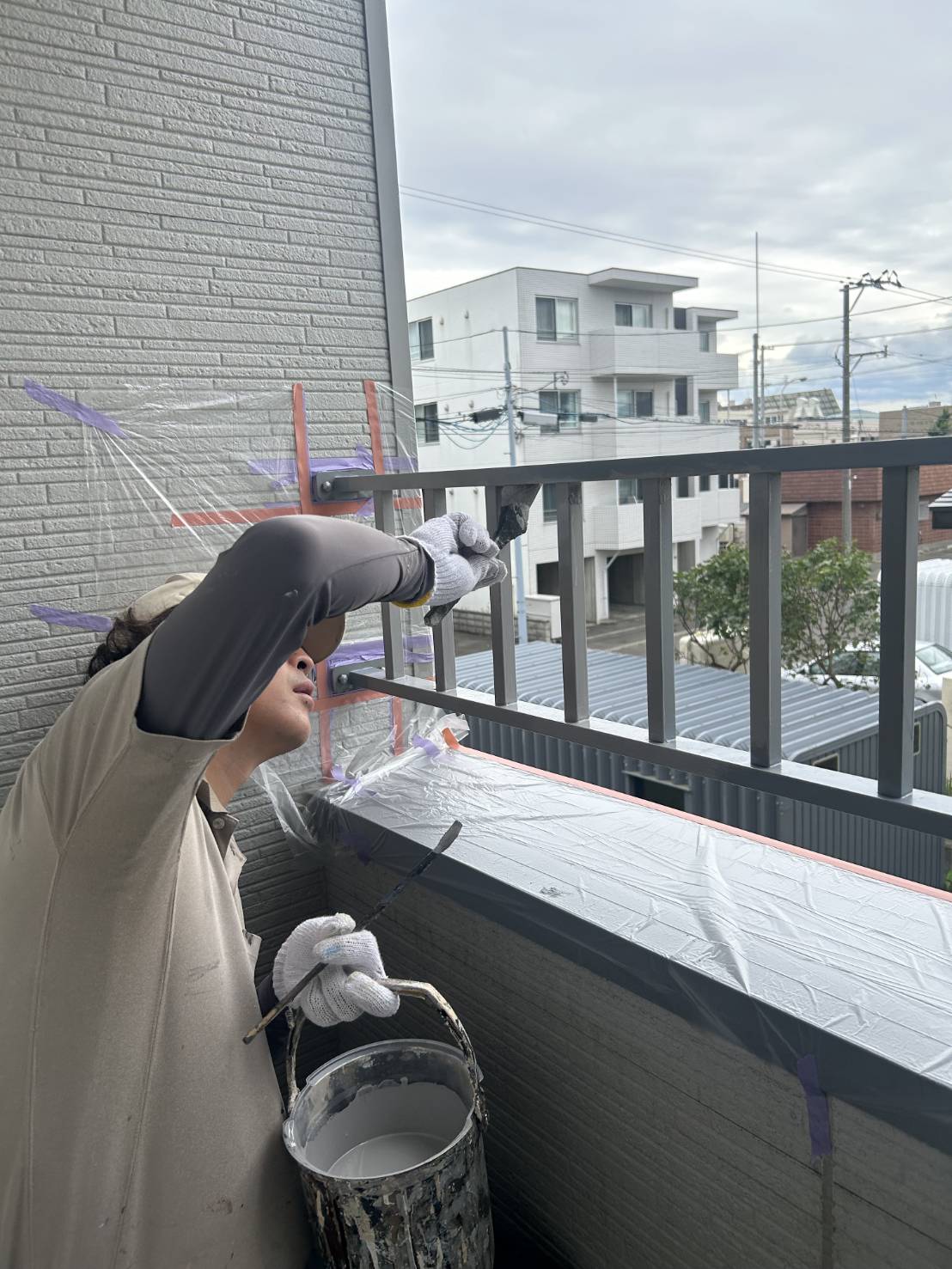 ベランダ手すりの表面を刷毛で塗装しているところ