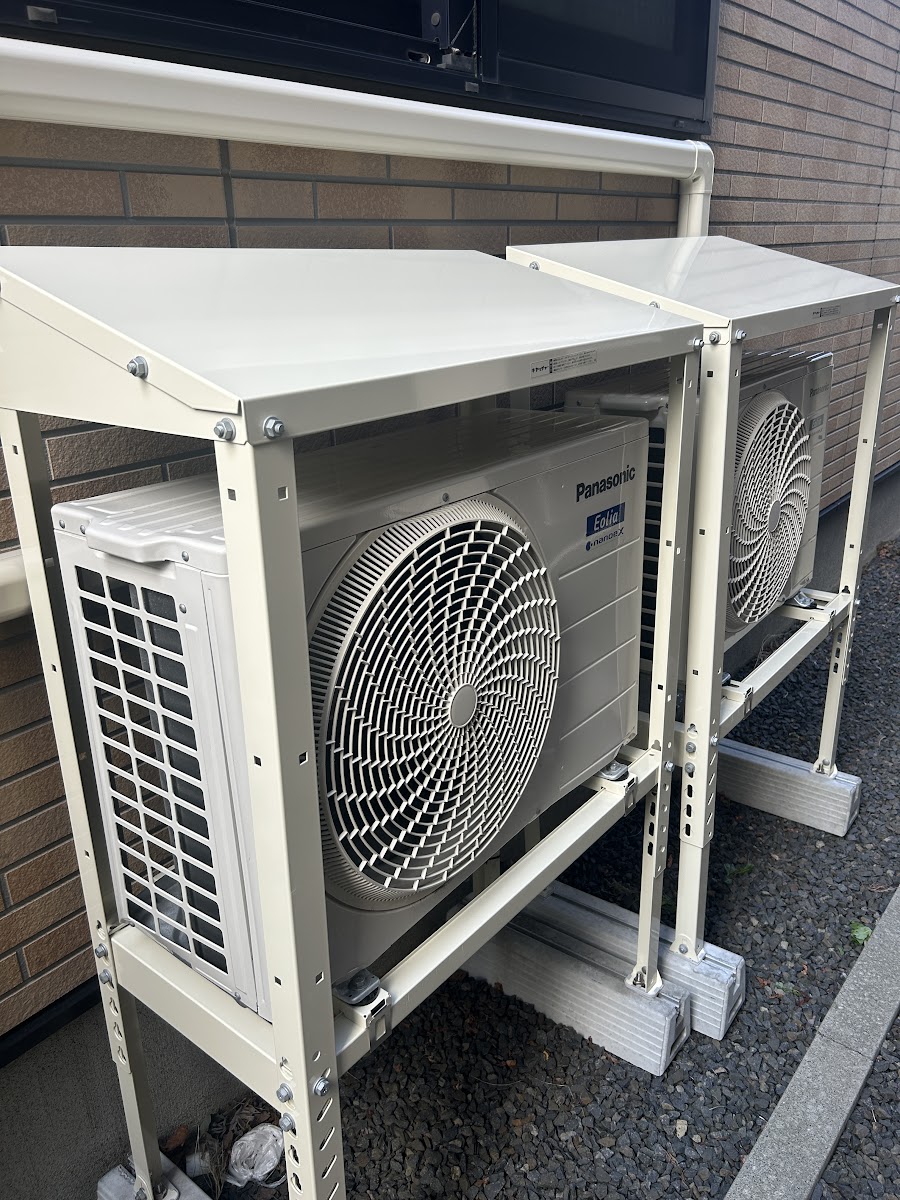 防雪屋根を取り付けた2台の室外機、窓の下に設置されている様子