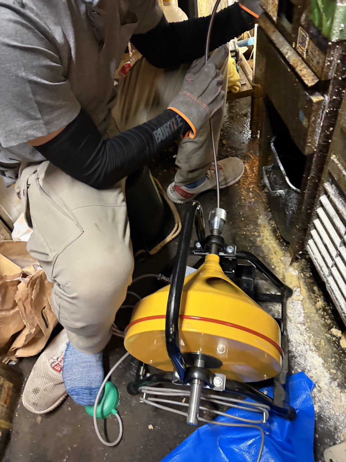 ドラム式の機械でワイヤーを排水管へ送り込む作業